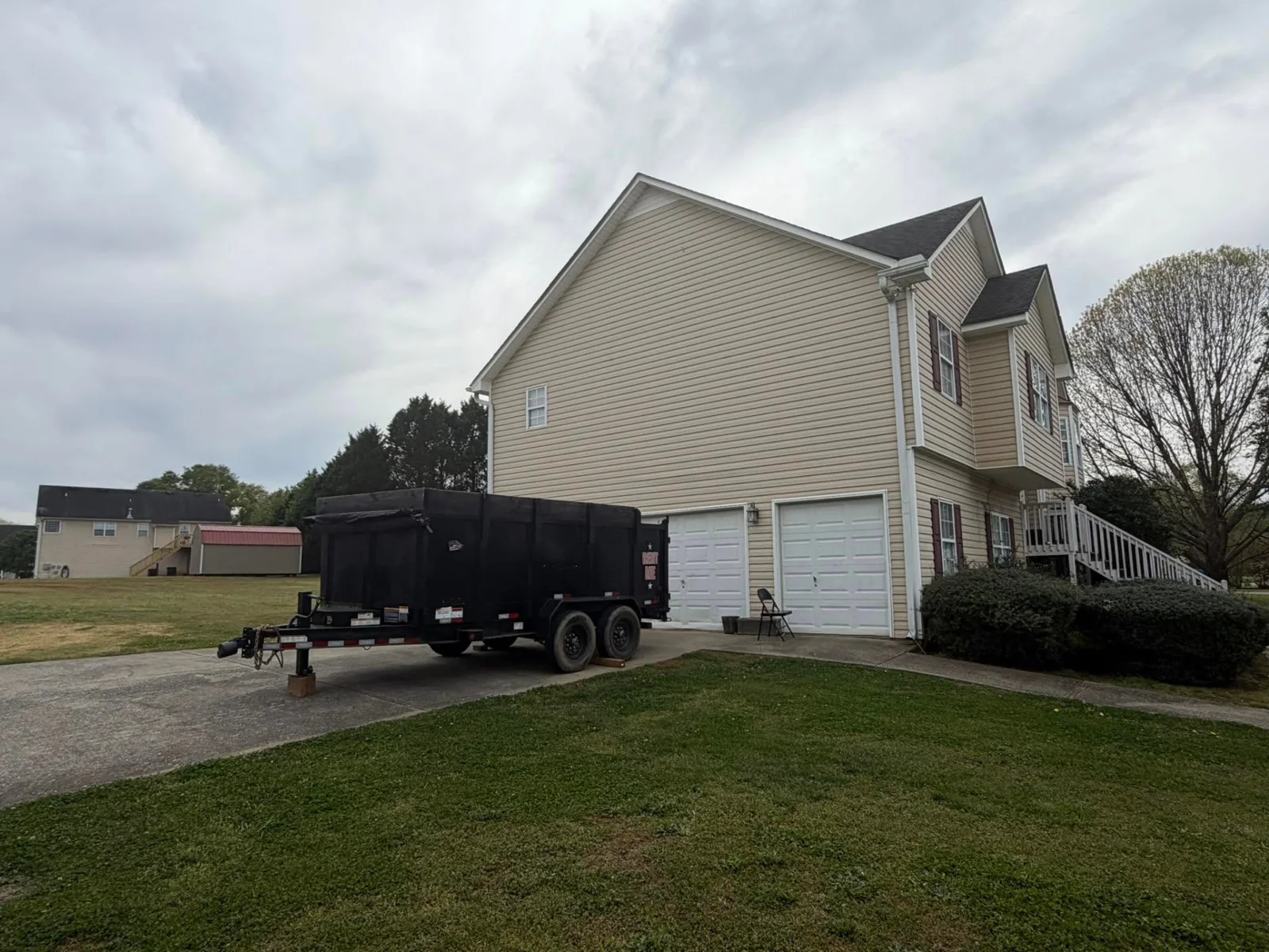 A black dump trailer parked in a residential driveway